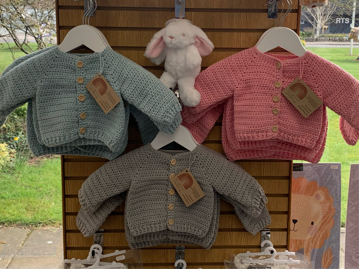 Light blue, grey and light pink baby cardigans in a local shop